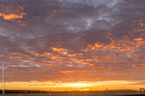 a large pink and red sky with clouds, and a car in the corner. 