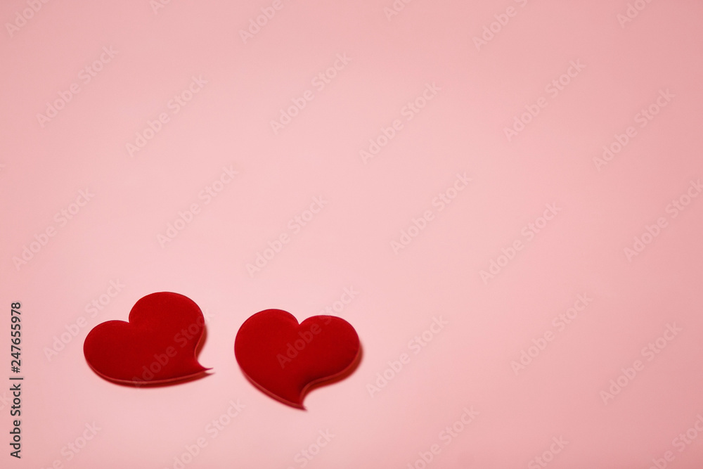 Two red velvet hearts in soft focus on a pink background. Background with copy space for Valentine's day or wedding