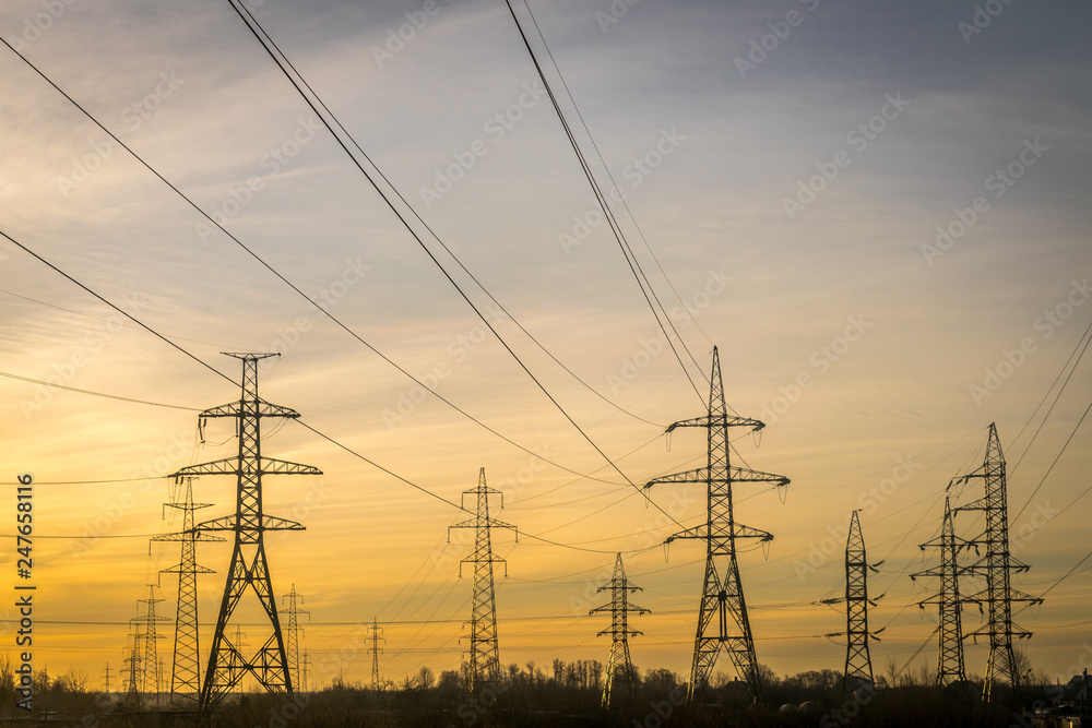 electric pylons with wires going into the distance at dawn or dusk. 