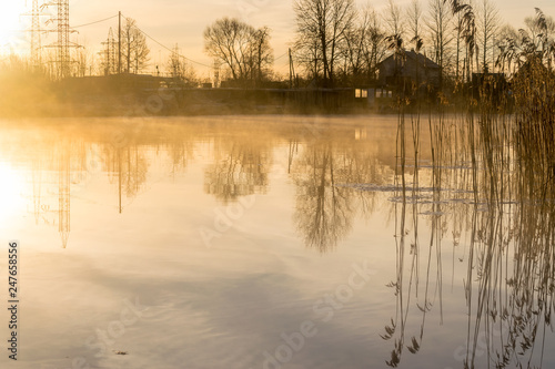 reflections on a pond at dawn or dusk, with mist or fog. 