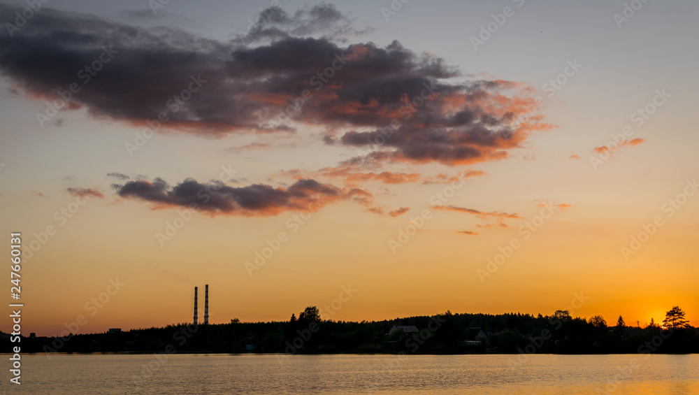 sunset or sunrise next to a reservoir with an industrial factory and chimneys.  