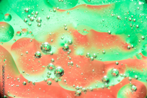 oil bubbles in water close up on a red green background