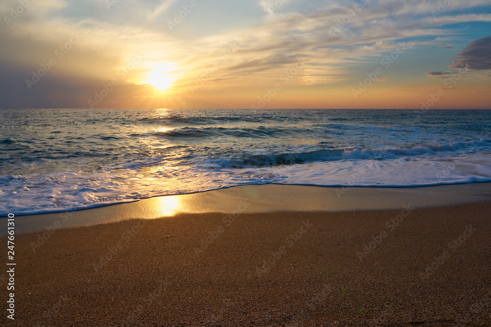  Tropical sandy beach. Sunset seascape. Waves with foam hitting sand.