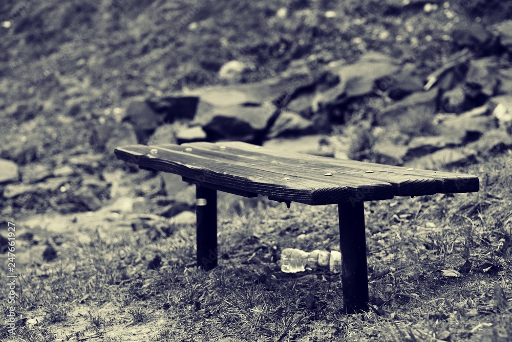 Black and white photo of wood bench, with discarded plastic bottle Black and white photo of wood bench, with discarded plastic bottle
