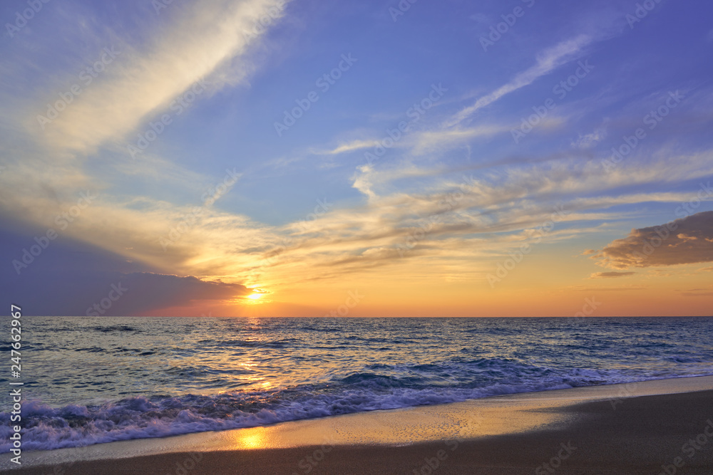 Obraz premium Tropical sandy beach. Sunset seascape. Waves with foam hitting sand.