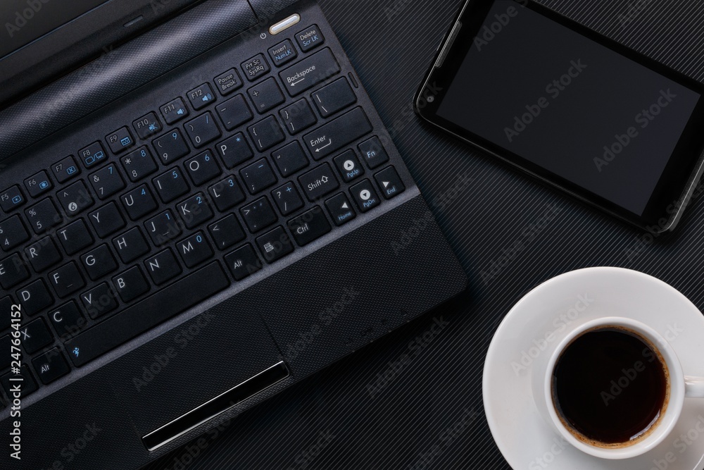 laptop with smartphone and cup of coffee on black textured surface. flat lay laptop with smartphone and cup of coffee on black textured surface. flat lay