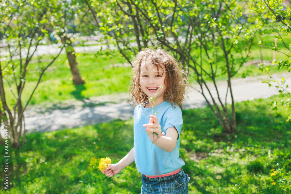The girl gives her mother a dandelion flower. Happy baby on a walk. Widely smiling beautiful girl on a background of grass and bushes in spring. Mothers Day. Women's Day. March 8 The girl gives her mother a dandelion flower. Happy baby on a walk. Widely smiling beautiful girl on a background of grass and bushes in spring. Mothers Day. Women's Day. March 8