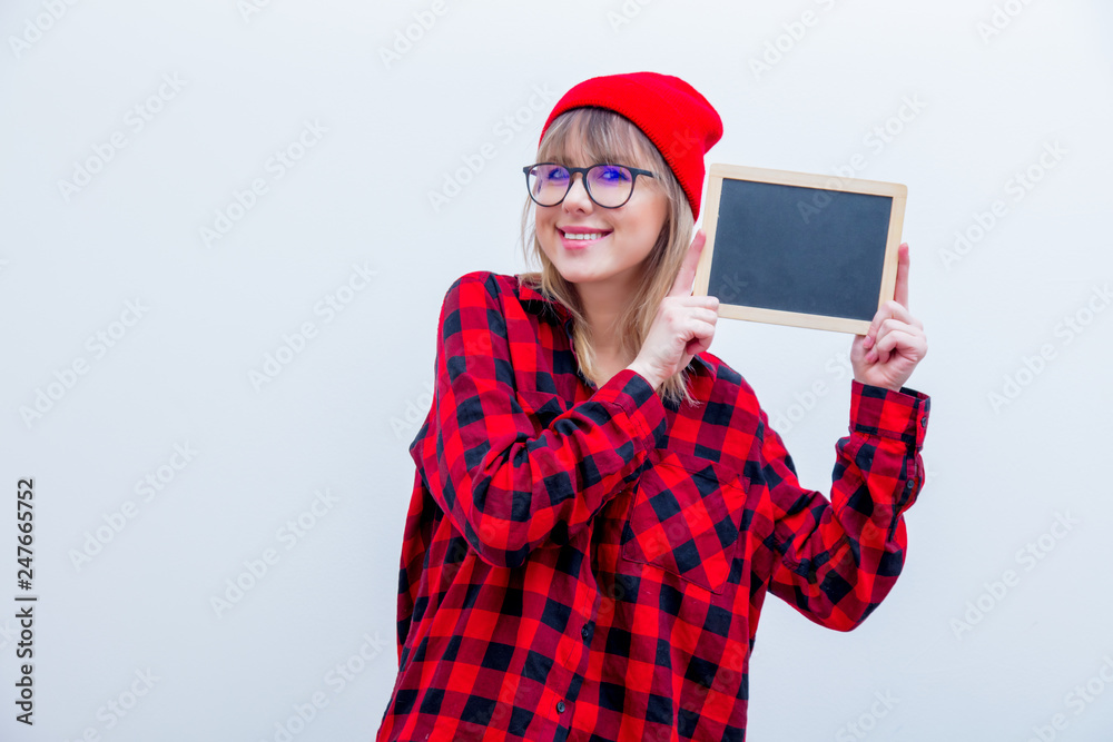 Fototapeta premium Young woman in red shirt and hat with blackboard