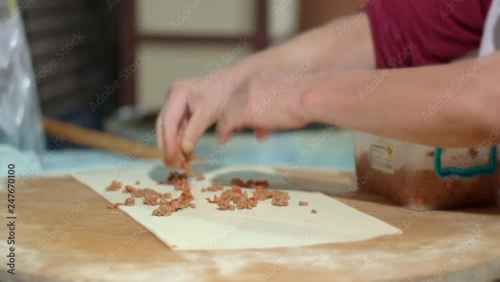 Hands lay out meat filling in preparation of pita. Process of making lavash Hands lay out meat filling in preparation of pita. Process of making lavash