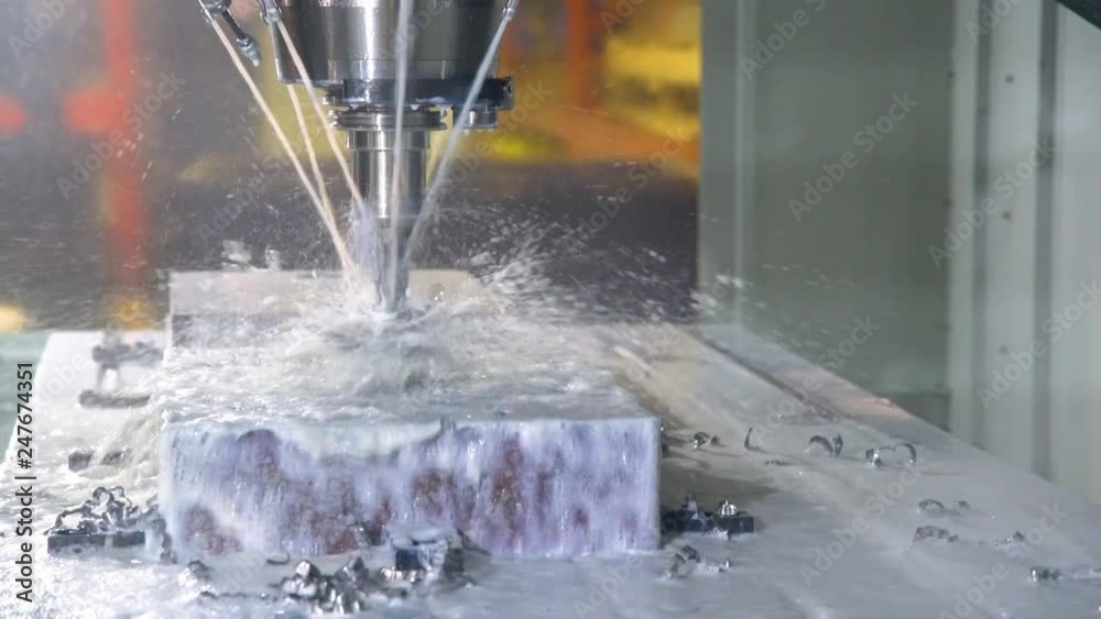 CNC milling machine in operation in an industrial machine shop. CNC milling machine in operation in an industrial machine shop.