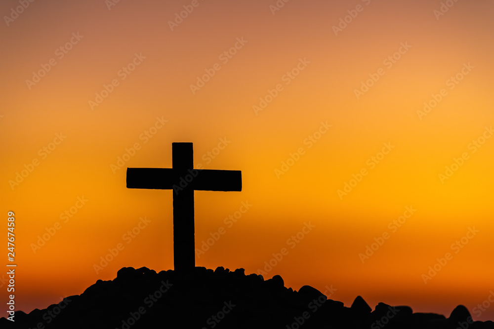 The silhouette of the cross across the mountain at sunset