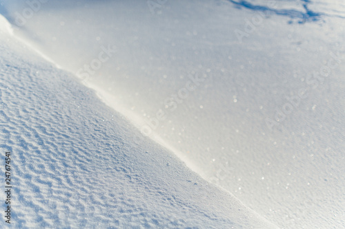 Texture of frosty snow, selective focus on left side of the frame, right side blurred/ frosty winter day, cold snap, frozen lake, little snow dunes due to the wind on the lake, copy space.