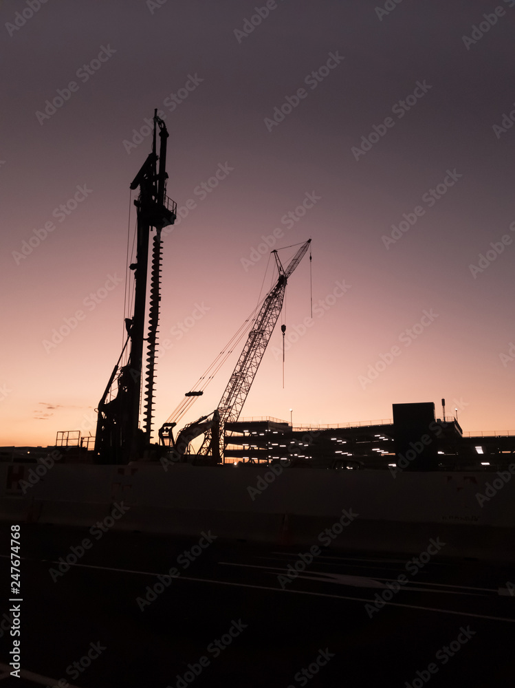 Fotografie Construction equipment silhouetted against evening sky.