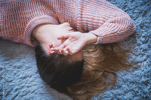 Sleepy woman laying on the carpet with her hand covering part of her face.