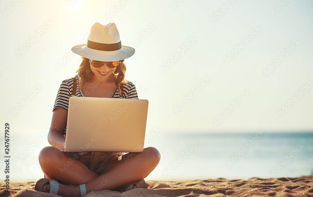 young woman working with laptop on nature in beach.