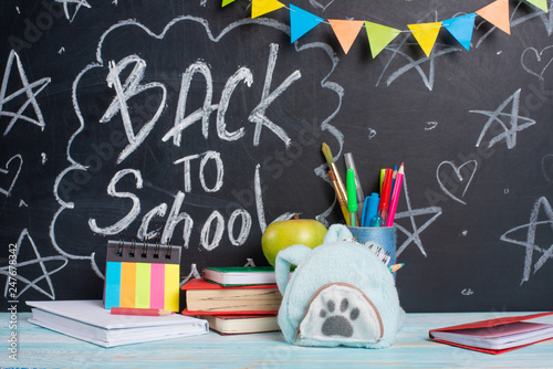 The inscription back to school on the blackboard with school supplies. The concept of study