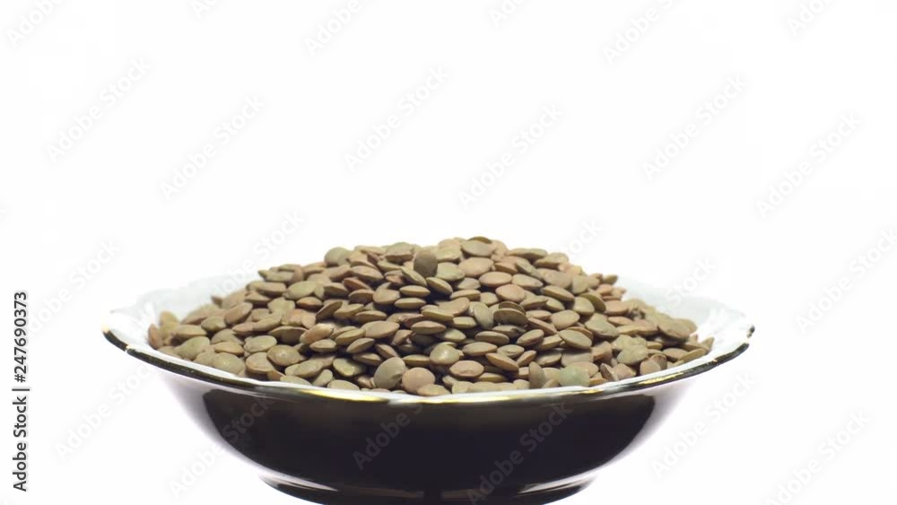 Lentils. Rotation. Close up. Heap of raw uncooked brown lentils in a bowl in rotation. Food background. Isolated on white, studio shot. Healthy organic food diet concept Lentils. Rotation. Close up. Heap of raw uncooked brown lentils in a bowl in rotation. Food background. Isolated on white, studio shot. Healthy organic food diet concept