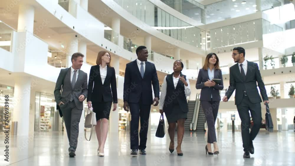 Group of six multiethnic business colleagues in formal clothes walking to meeting and talking to each other