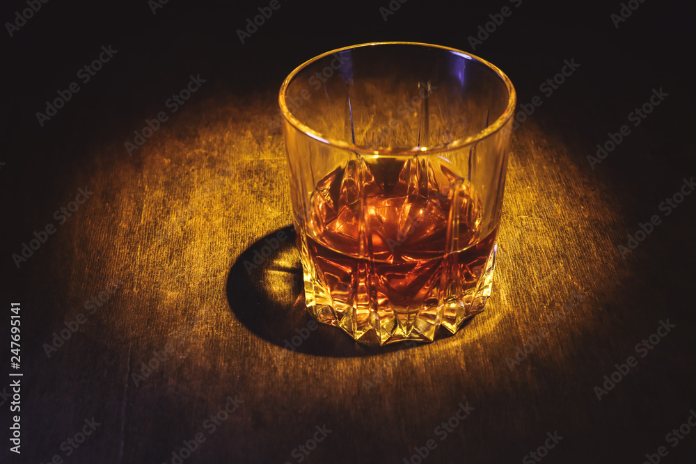 Whiskey in a glass on a dark wooden background.