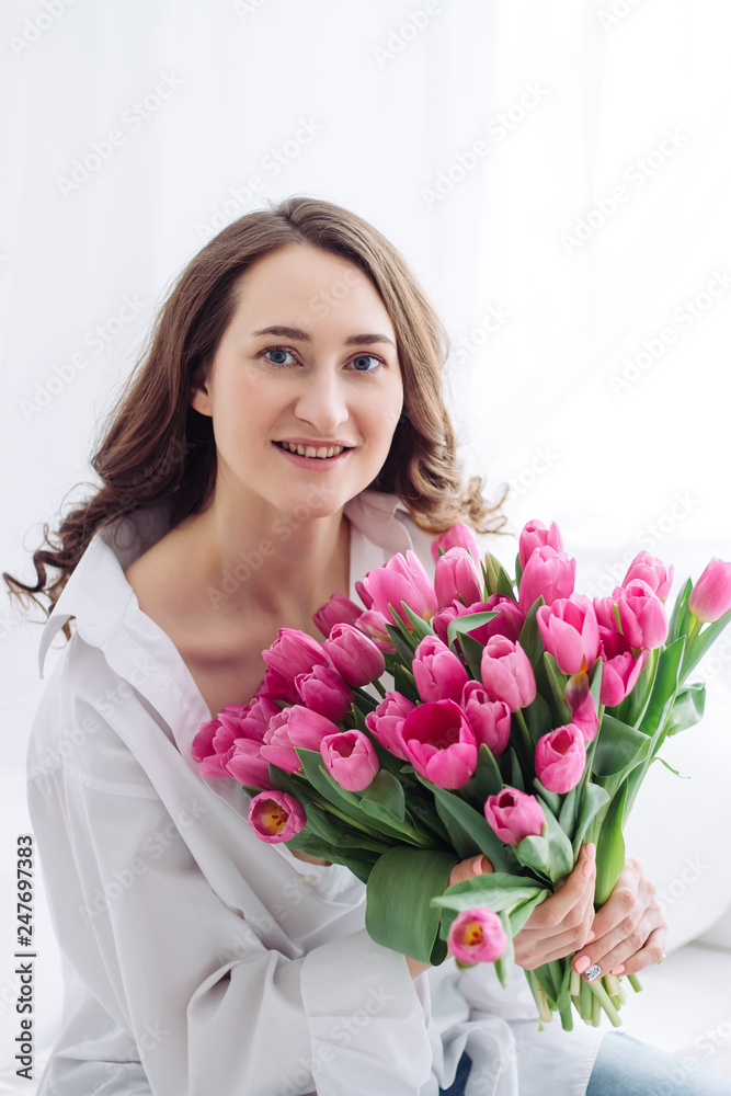 Portrait of young woman with pink tulips. White shirt Portrait of young woman with pink tulips. White shirt