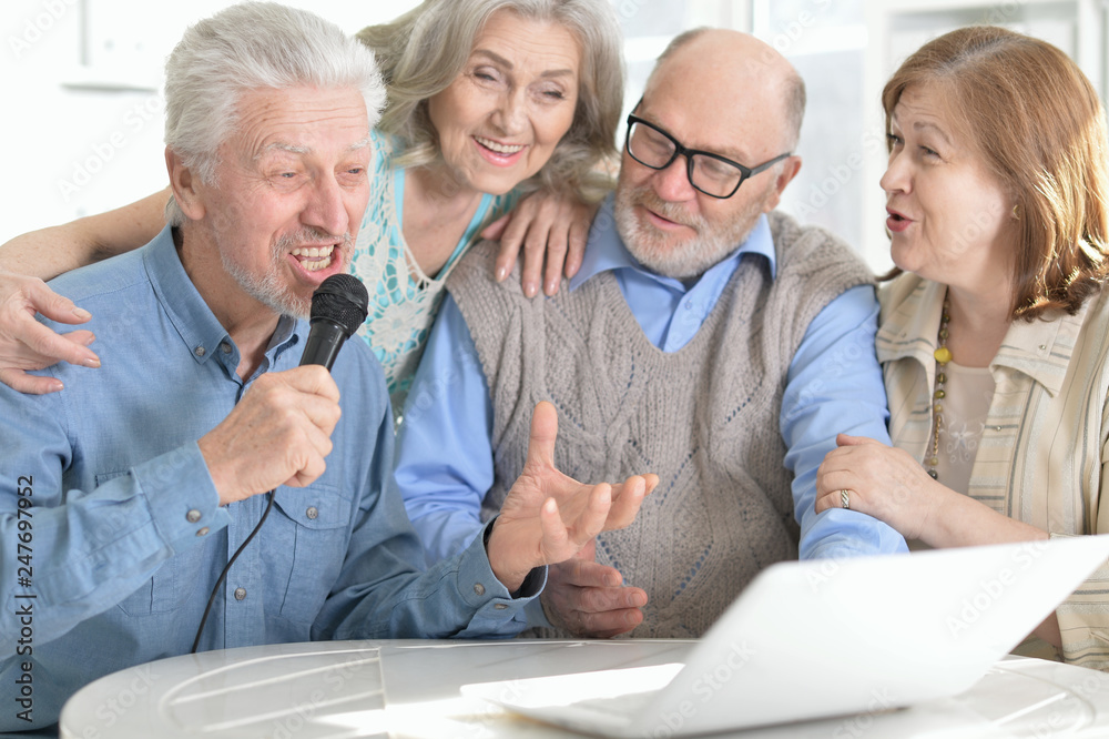Portrait of two senior couples sitting at table and singing karaoke Portrait of two senior couples sitting at table and singing karaoke