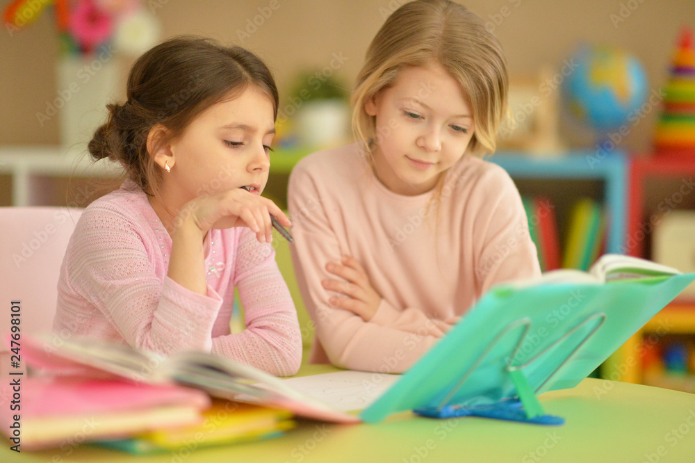 Fototapeta premium Portrait of little girls doing homework together