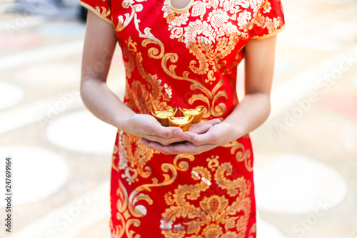 Beautiful asian woman wear cheongsam and holding gold bars as gifts for the Chinese New Year for you. Happy Chinese New Year festival.