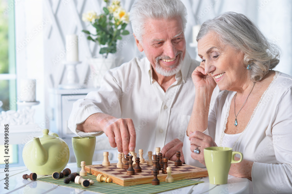 Portrait of happy senior couple playing chess together