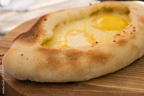 Adjarian khachapuri in restaurant on wooden plate. photo