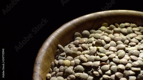 Lentils. Rotation. Close up. Heap of raw uncooked brown lentils in a bowl in rotation.  Food background.  black background, studio shot. Healthy organic food diet concept photo