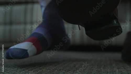 A man puts a brown dress shoe on his foot. photo