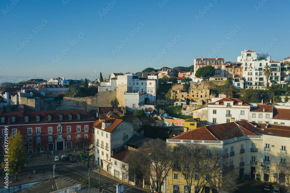 Beautiful panoramic Lisbon landmark with tiny houses with moorish architectural elements on the hill; drone view of picturesque labyrinth of narrow streets and small squares in early morning, Portugal
