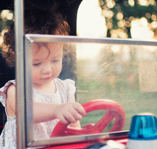 A child behind the wheel of a toy car. Toddler girl in the carousel amusement park © Nikita Vasilchenko