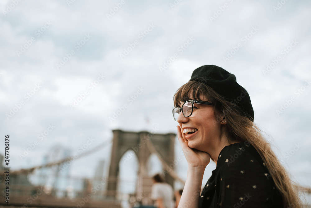 Smiling woman wearing beret with Brooklyn Bridge in background