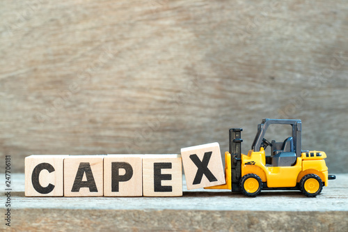 Toy forklift hold letter block x to complete word capex (abbreviation of capital expenditures) on wood background photo