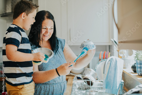 Obraz na plátně Mother teaching son how to do the dishes