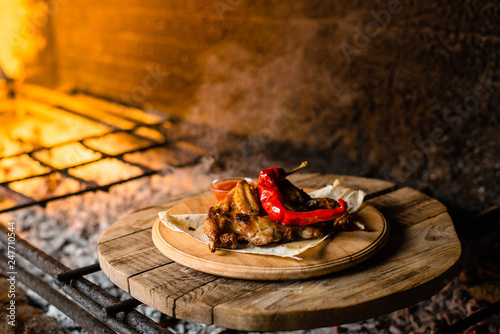 grilled chicken on a pita in a clay plate, against the background of brazie photo