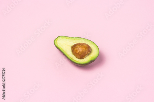 Half avocado on a pink background. Healthy eating concept.