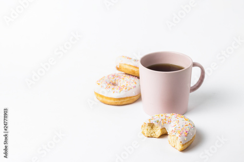 Pink Cup with coffee or tea and fresh tasty donuts  sweet multicolored decorative candy on a white background. Bakery concept  fresh pastries  delicious breakfast  fast food.