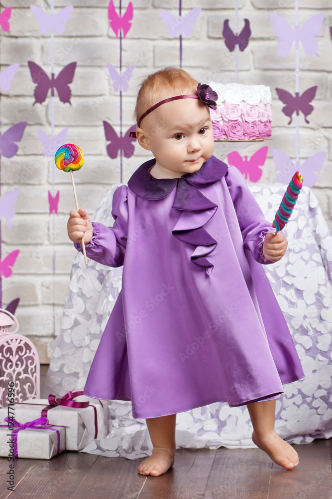 Little happy toddler girl celebrating first birthday. Cute baby girl with candy Little happy toddler girl celebrating first birthday. Cute baby girl with candy