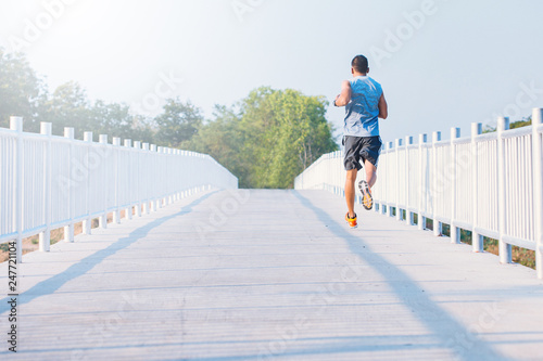 young man runner running on running road in city park