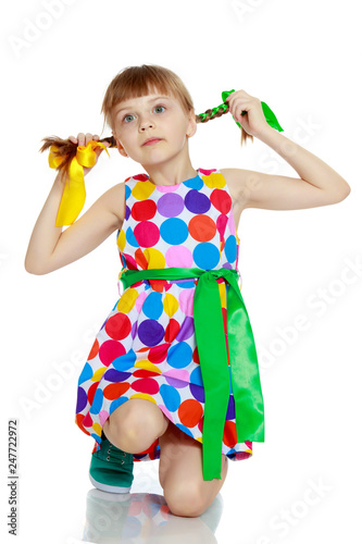 A little girl in a dress with a pattern from multi-colored circl