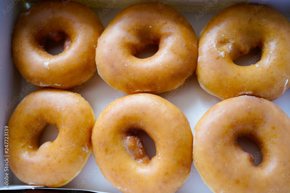 A dozen of Golden glazed Doughnuts in the box