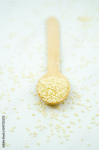 White sesame on wooden spoon isolated on white background.