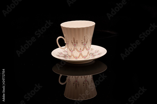 white glass with a saucer on a black background