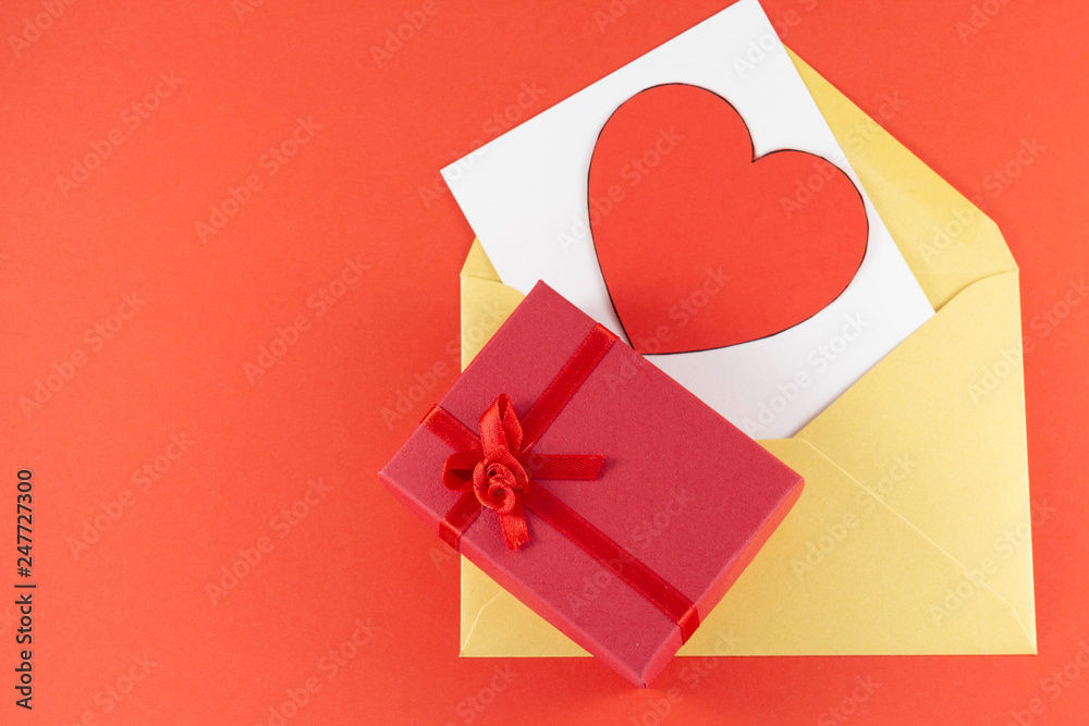 Yellow open envelope with white blank letter inside Big heart red color with big red gift box on a red background Letter or invitation Minimalist concept Copy Space and template