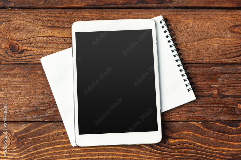 Tablet with notepad on wooden background Tablet with notepad on wooden background