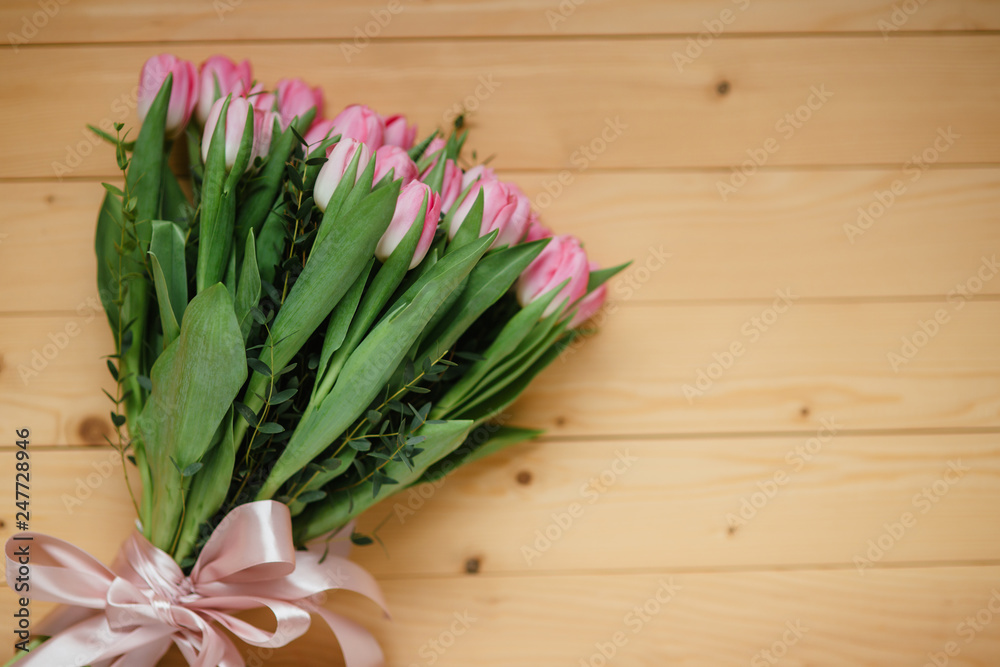 Bouquet of bright pink tulips with a beautiful bow on a wooden background Bouquet of bright pink tulips with a beautiful bow on a wooden background