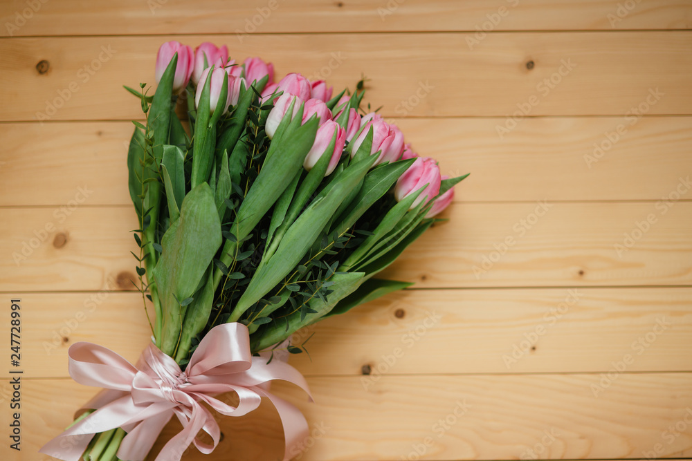 Bouquet of bright pink tulips with a beautiful bow on a wooden background Bouquet of bright pink tulips with a beautiful bow on a wooden background