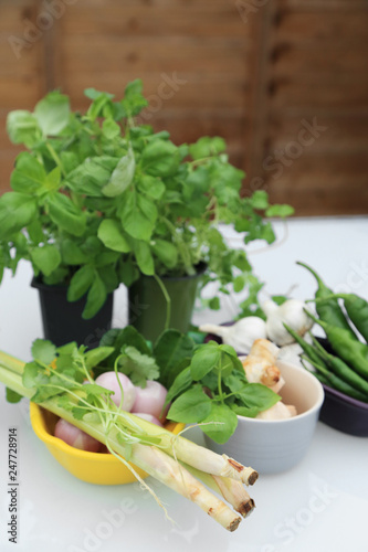 Fresh green garden for cooking - basil, parsley, chilli, lemon grass , galangal, garlic, shallot, kaffir lime leaves on white table.